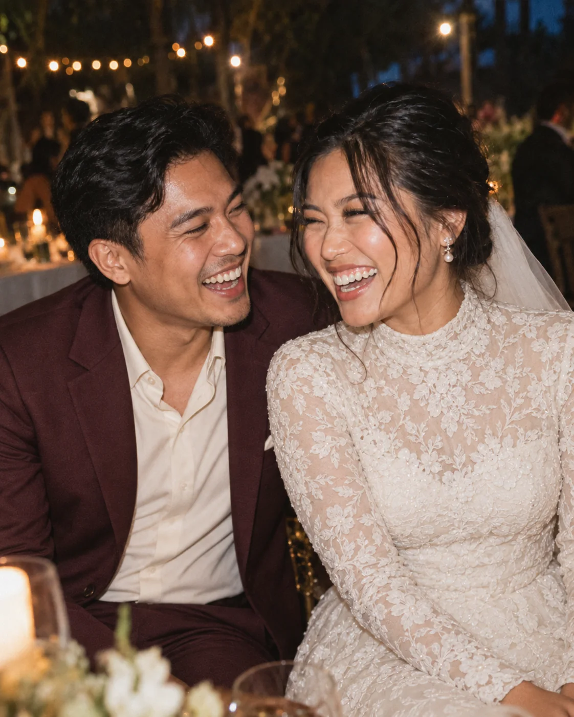 A bride and male wedding guest caught in a joyful laugh at an evening reception